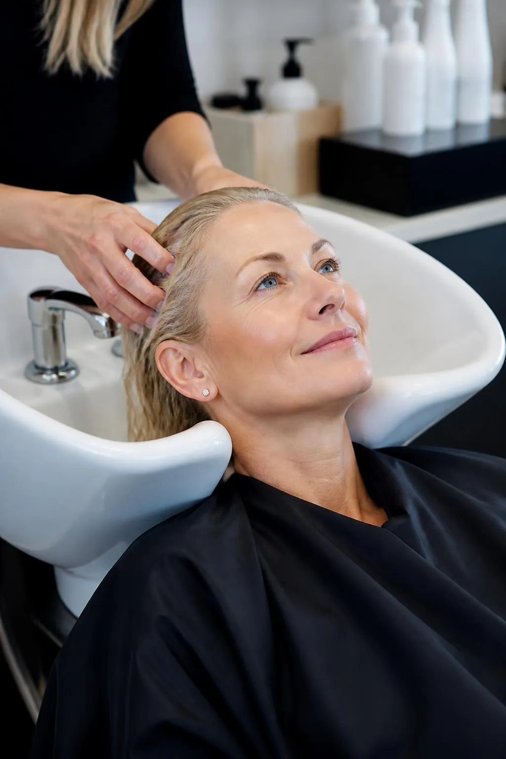 Blonde woman enjoying a relaxing hair wash at the salon basin